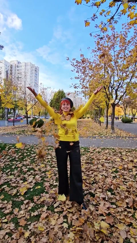 A beautiful red-haired girl  throws fallen maple leaves Stock Footage 327084549