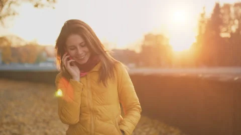 Beautiful red-haired smiling young woman talking on a cell phone in autumn park Stock Footage 99919293