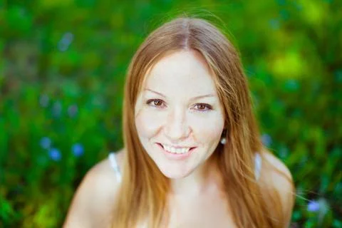 Beautiful red-haired smiling young woman sitting on the grass Stock Photos