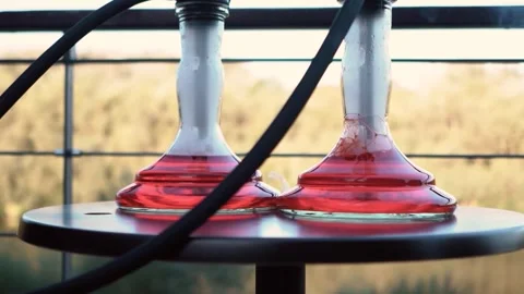 Beautiful red hookah flasks stand on the pier on the river bank. Outdoor Stock Footage 263496522