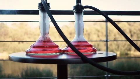 Beautiful red hookah flasks stand on the pier on the river bank. Outdoor Stock Footage 263496543