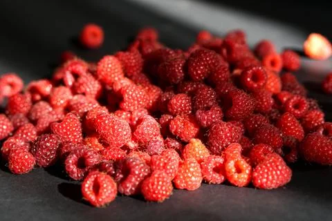 Beautiful red sunlit raspberry on black table Stock Photos