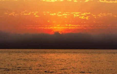 Beautiful red sunset, dark clouds and ocean on the horizon Stock Photos