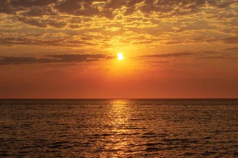 Beautiful red sunset, dark clouds and ocean on the horizon Stock Photos