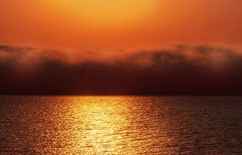 Beautiful red sunset, dark clouds and atlantic ocean on the horizon Stock Photos