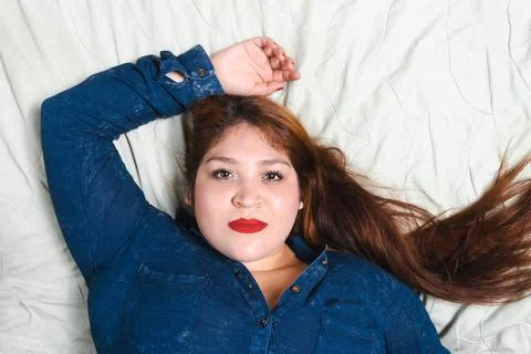 Beautiful redhead plus size model lying in bed smiling. young fat model Stock Photos