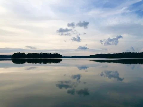 Beautiful reflection of evening sky, clouds and trees in the calm lake's water Stock Photos