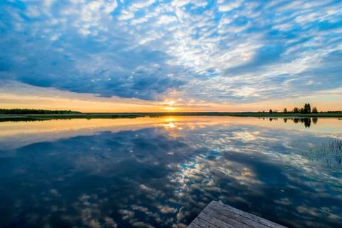 Beautiful reflection of the sky in the calm surface of the lake in the mornin Stock Photos