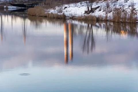 Beautiful reflection of trees and tall pipes in the mirror smooth surface of Stock Photos