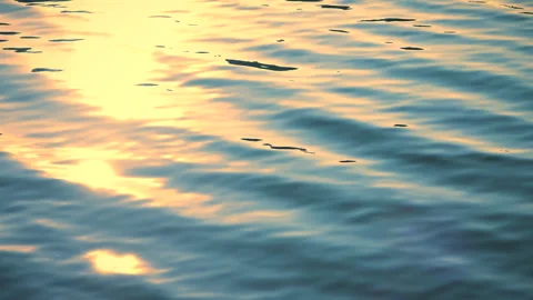 Beautiful reflection yellow sunset light on blue water, rippled waves. 스톡 동영상 251426945