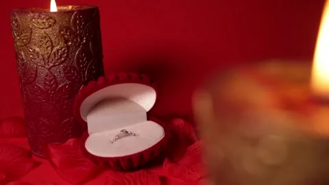 A beautiful ring in a red velvet shell. Rose petals, background, candle. Empty Stock Footage 145680500