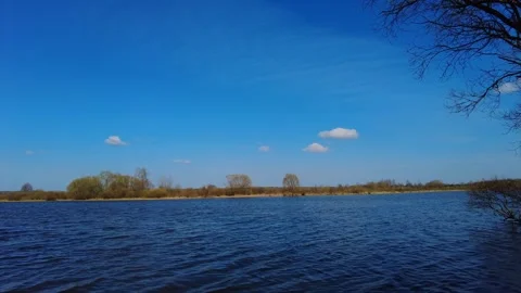 Beautiful river flow under a clear sky with soft clouds and trees along the shor Video stock 333440649