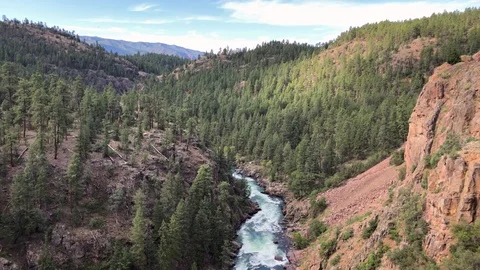Beautiful river flows through a lush green canyon far below, viewed from a train Stock Footage 113875725