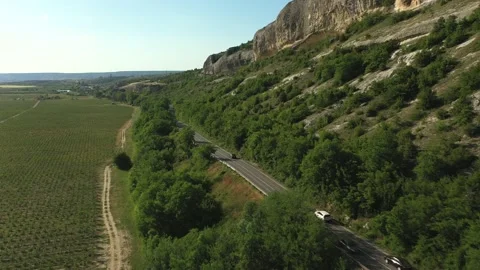 A beautiful road among the fields, valley, rocky ridges, hills and mountains. Stock Footage 165496772
