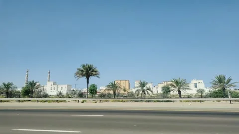 A beautiful road lined with palm trees against a clear blue sky above, Emirates Vídeo Stock 291552605