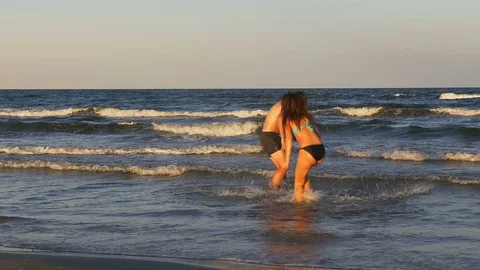 Beautiful romantic young couple teasing one another and playing in the sea Stock Footage 70610682