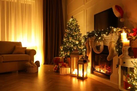 Beautiful room interior with fireplace and Christmas decor in evening Stock Photos