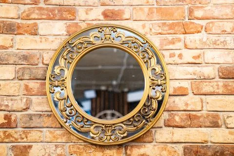 Beautiful round mirror with pattern on a metal frame on a brick wall. Foto stock