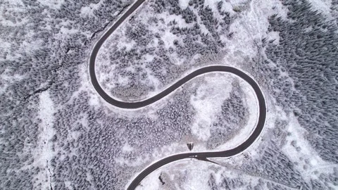 Beautiful S-shaped bend of winter road through hills and forest in mountains Stock Footage 257299860