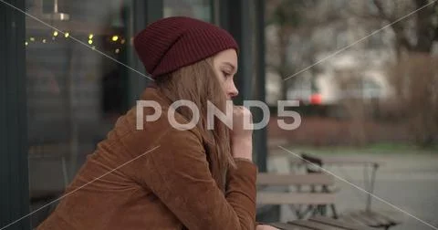 Beautiful sad woman sitting alone in outdoors restaurant. Stock Photos