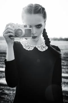 Beautiful sad young girl photographing on vintage film camera. Black and whit Stock Photos