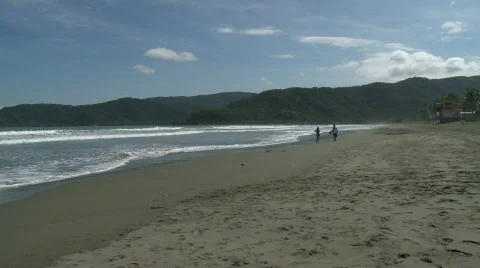 Beautiful sand beach with waves rolling in slowly and a couple in the distance  Video stock 608264