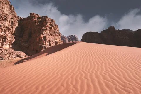 Beautiful sand dune in the background of cliffs in the hot Wadi Rum Desert Jo 스톡 사진