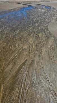 Beautiful sand pattern on beach during outflow with blue glare of the sky Stock Photos