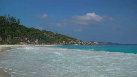 Beautiful sandy beach with blue sky and ocean waves on an exotic island Stock Footage 107510195