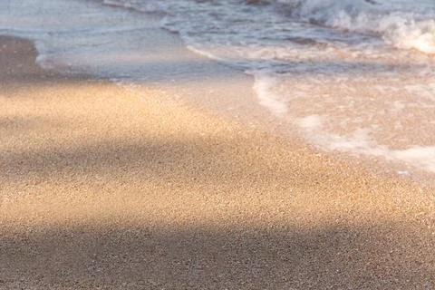 Beautiful sandy beach with sunlight with shadows and blue ocean wave Stock Photos