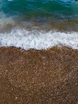 Beautiful sea background with pebble beach and blue waves with sea foam. Stock Photos