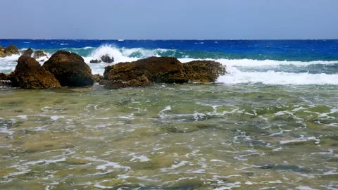Beautiful seascape. small surf waves with white foam, breaking on rocky beach of Stock Footage 136747320