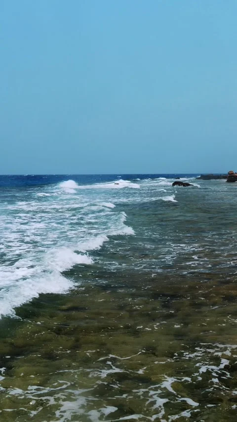 Beautiful seascape. small surf waves with white foam, breaking on rocky beach of Stock Footage 322711364