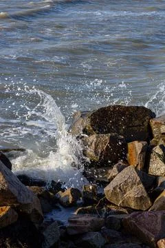 A beautiful seashore with a wave and big stones Stock Photos