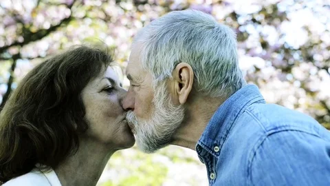 Beautiful senior couple in love outside in spring nature kissing. Stock Footage