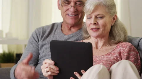Beautiful senior couple using tablet on couch Stock Footage