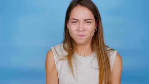 Beautiful serious woman in gray t-shirt angry on blue background with copy space Stock Footage 137317841