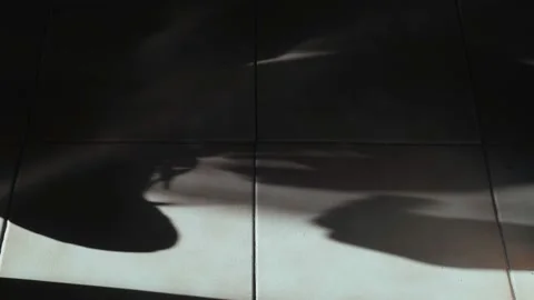 Beautiful shadow on the tiled floor. Silhouette of hands tying shoelaces. Moving Stock Footage 154617153