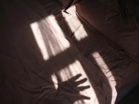 Beautiful shadow from the window and hand on the bed from the morning sun Stock Photos