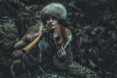 Beautiful shamanic girl playing on shaman flute in the nature. Stock Photos
