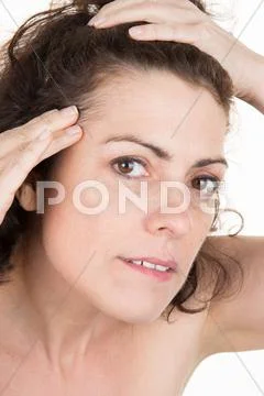 Beautiful shocked woman checking her first wrinkles on forehead Stock Photos