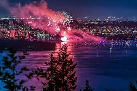 Beautiful shot of bright colorful exploding fireworks in a city over water Stockfoto's