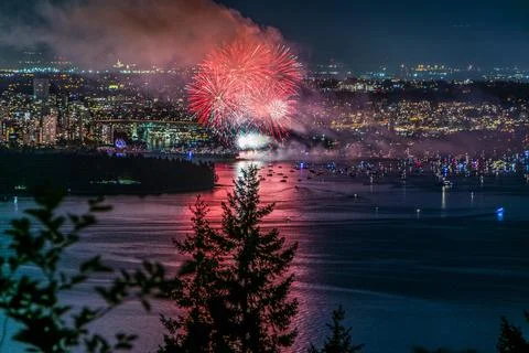 Beautiful shot of bright colorful exploding fireworks in a city over water Foto stock