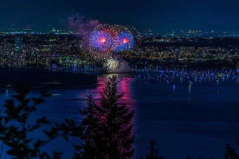 Beautiful shot of bright colorful exploding fireworks in a city over water Foto stock