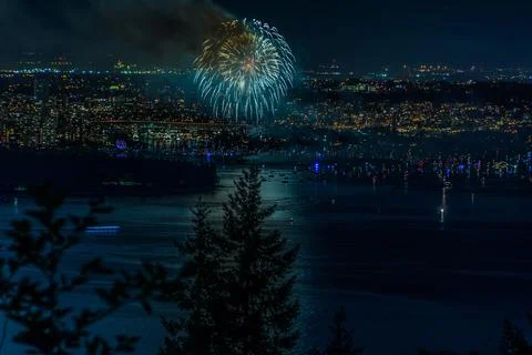 Beautiful shot of bright colorful exploding fireworks in a city over water Stock Photos