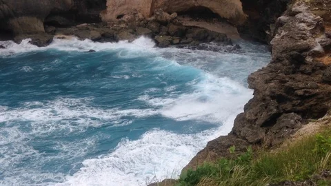 Beautiful Shot Of Deep Blue Waves Crashing Against Rock Cliff, Bali, Indonesia Stock Footage 104729174