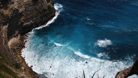 Beautiful Shot Of Deep Blue Waves Crashing Against Rock Cliff, Bali, Indonesia Stock Footage 115915221