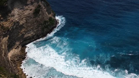 Beautiful Shot Of Deep Blue Waves Crashing Against Rock Cliff, Bali, Indonesia Stock Footage 115915331