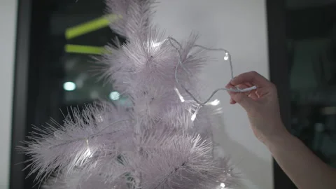 Beautiful shot of hands puts lights on a white Christmas Tree, decorating Stock Footage 137510042