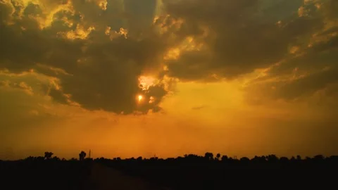 Beautiful shot of sunset behind clouds with silver lining and rays in rural  Stock Footage 210851912